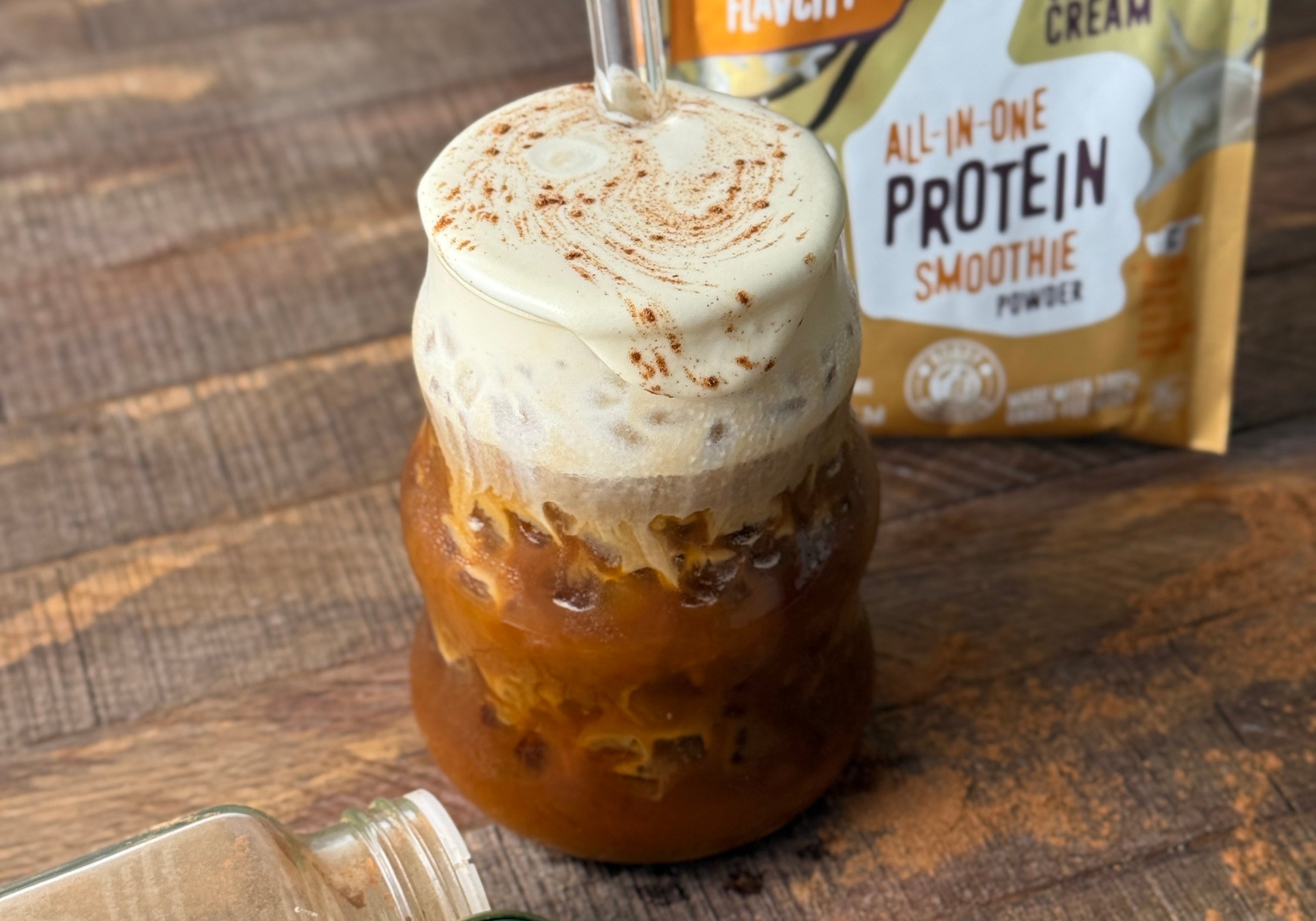 cold protein foam in a glass with a glass straw and flavcity vanilla cream protein smoothie mix