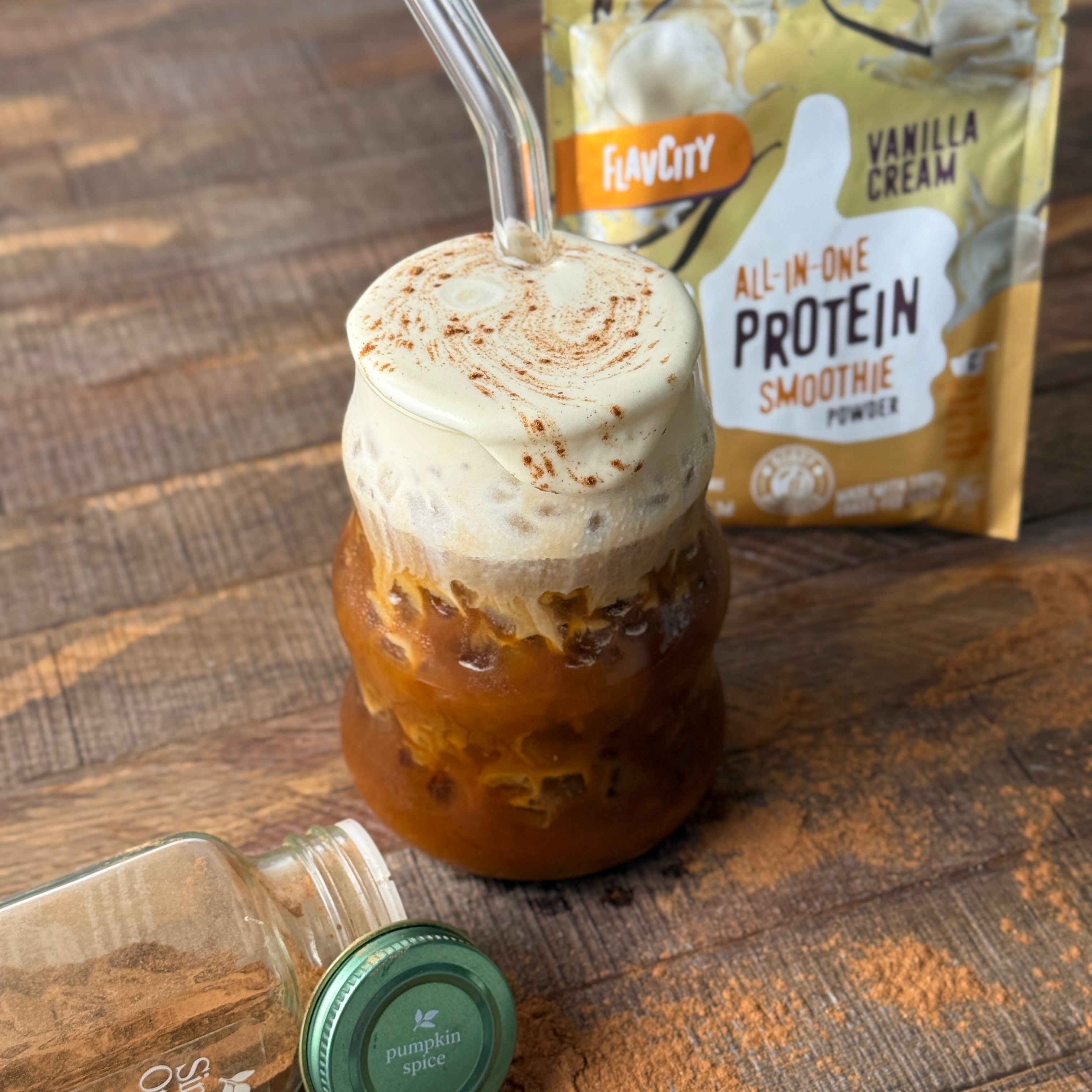 cold protein foam in a glass with a glass straw and flavcity vanilla cream protein smoothie mix