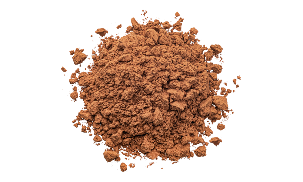 A pile of brown cocoa powder, with some chunks and small loose pieces, spread out on a white background.