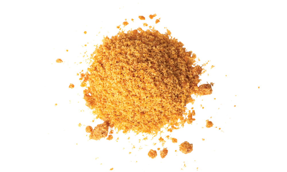 A pile of brown granulated powder, possibly brown sugar or spice, is scattered on a white background.