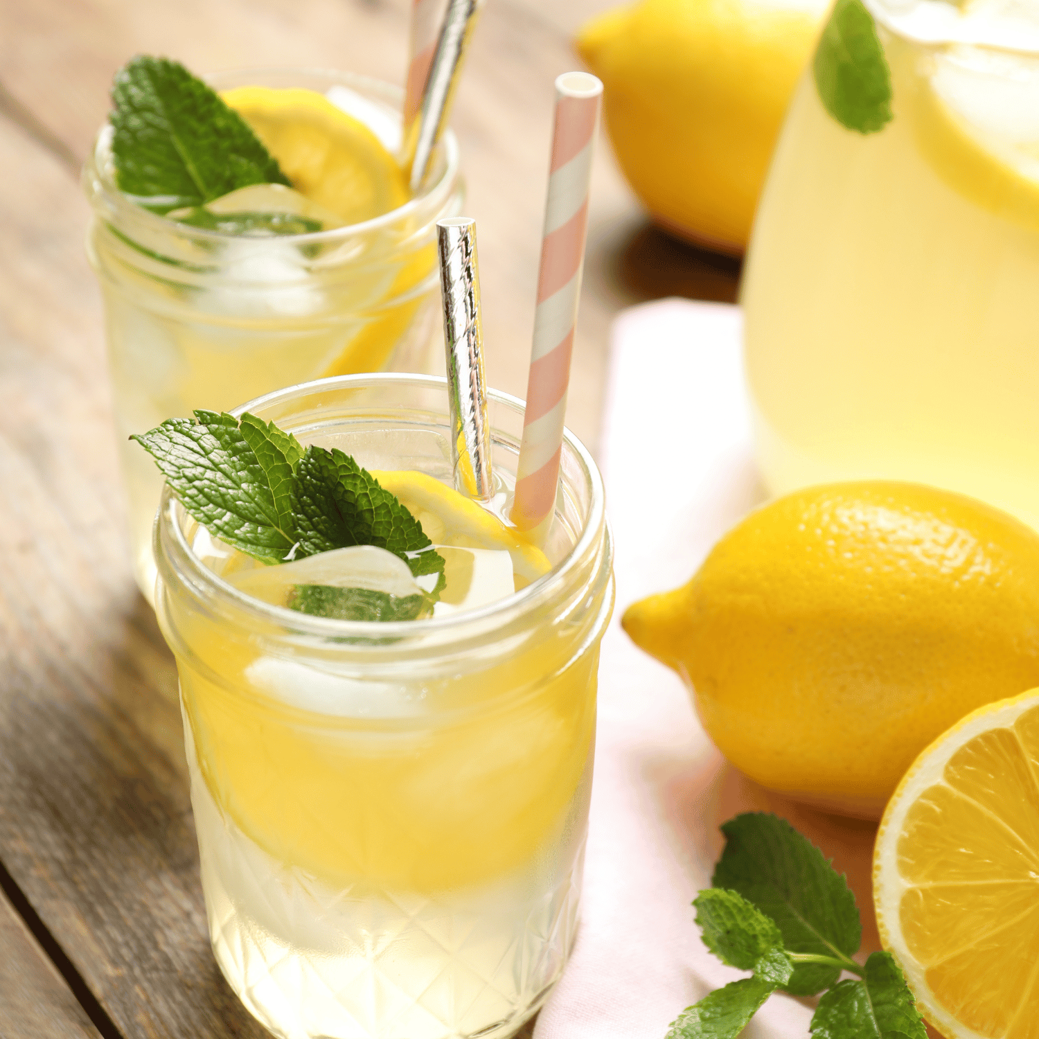 Two glass of lemonade and lemons on the table.