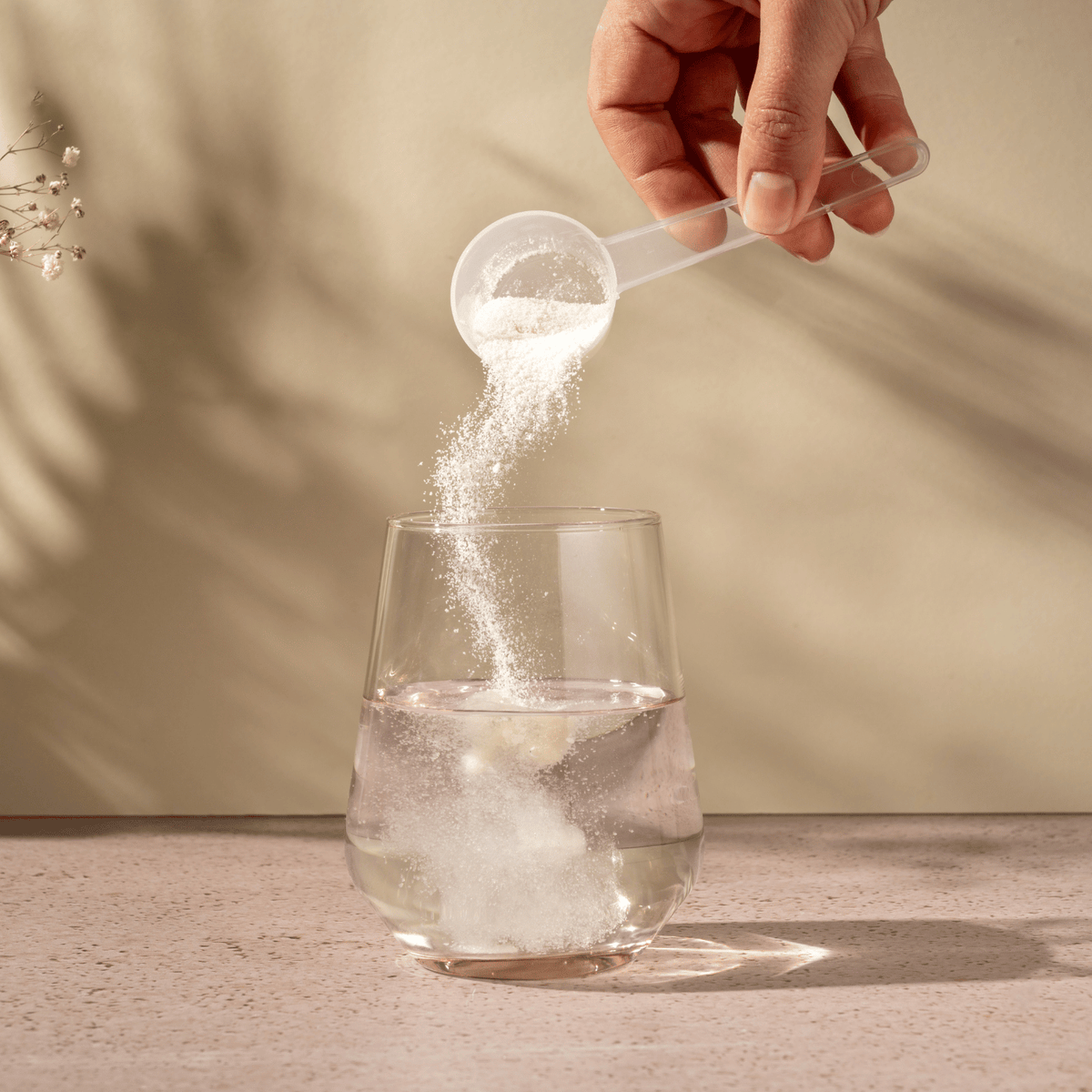 Pouring a collagen powder into the glass of water.