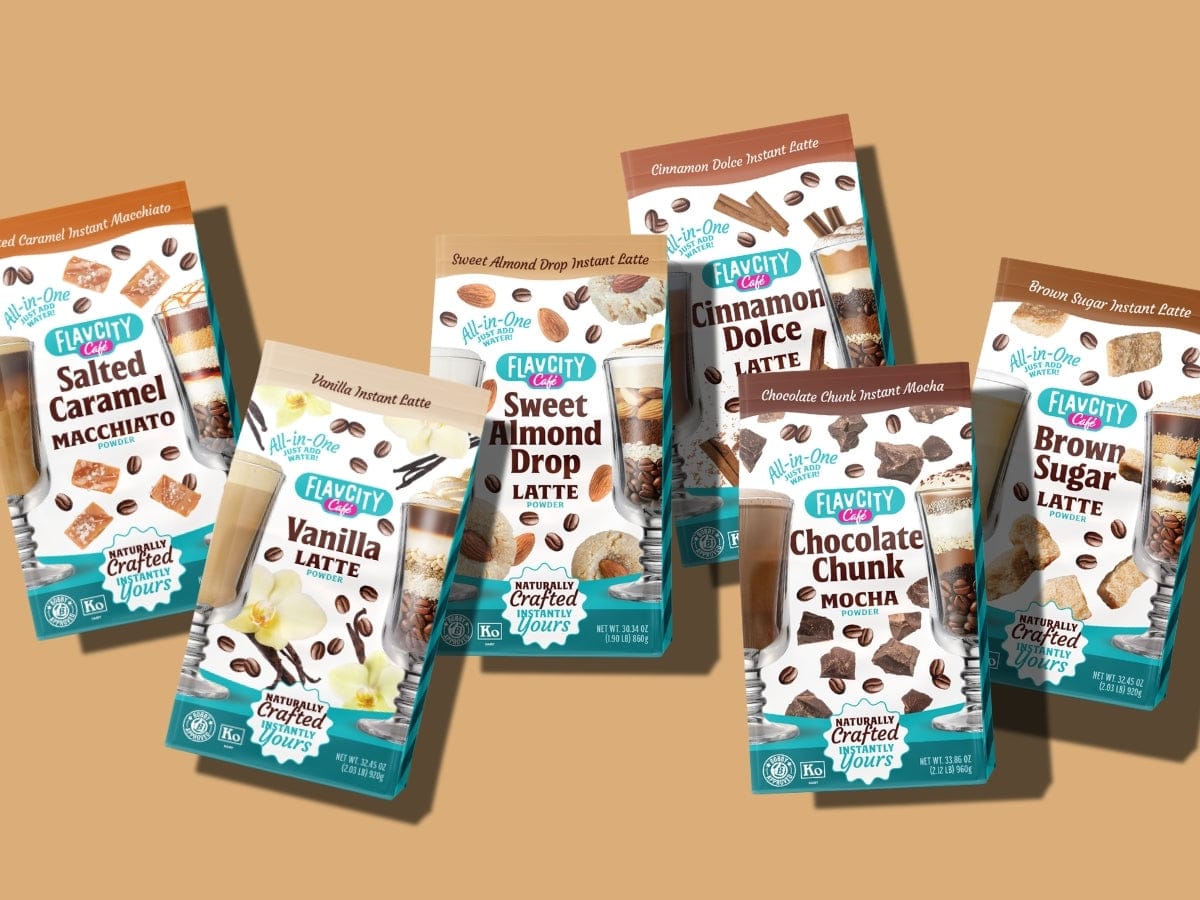 Six FlavCity instant latte mix packages, arranged on a tan background, featuring flavors like Salted Caramel Macchiato, Vanilla Latte, Sweet Almond Drop Latte, Chocolate Chunk Mocha, Cinnamon Dolce, and Brown Sugar Latte.