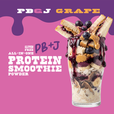 A tall glass layered with a PB&J Grape Protein Smoothie, banana slices, and peanut butter, topped with grapes and a sandwich against a purple and pink background with text reading PB&J Grape and Gluten Free All-in-One Protein Smoothie Powder.