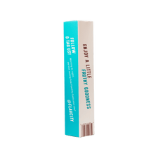 A rectangular FlavCity Frother box stands upright. One turquoise side has white text: follow and tag @FLAVCITY; the other white side features brown and turquoise text: ENJOY A LITTLE FROTHY GOODNESS—perfect for your latte frother. Brand: FlavCity Cafe.