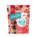 A pouch of Shop FlavCity Berries & Cream Protein Smoothie powder next to a glass filled with the mix, surrounded by splashing milk, fresh strawberries, and collagen.