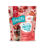 A pouch of Shop FlavCity Berries & Cream Protein Smoothie powder next to a glass filled with the mix, surrounded by splashing milk, fresh strawberries, and collagen.