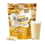A bag of Shop FlavCity Banana Bread Protein Smoothie stands next to a filled glass, banana slices, and chunks of banana bread on a white background.