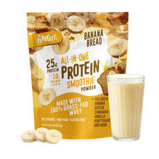 A bag of Shop FlavCity Banana Bread Protein Smoothie stands next to a filled glass, banana slices, and chunks of banana bread on a white background.