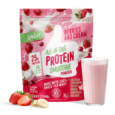 A bag of Shop FlavCity Berries & Cream Protein Smoothie sits next to a glass of pink smoothie, sliced strawberries, and banana on a white surface.