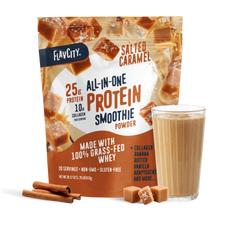 A bag of Shop FlavCity Salted Caramel Protein Smoothie stands behind a glass of the creamy salted caramel drink. Cinnamon sticks and caramel pieces are placed nearby, while the packaging showcases its protein, collagen, and featured ingredients.