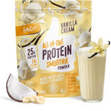 A pouch of Shop FlavCity Vanilla Cream Protein Smoothie sits next to a glass of vanilla protein smoothie, banana slices, coconut, and a vanilla flower, highlighting its grass-fed whey content and premium ingredients.