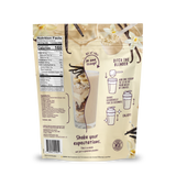 The back of the Shop FlavCity Vanilla Cream Protein Smoothie bag displays nutrition facts, a list of ingredients featuring grass-fed whey, and simple directions: mix one scoop with water or milk, shake well, and enjoy. The packaging is decorated with images of vanilla beans and a creamy smoothie. Slogan: Shake your expectations with every Vanilla Cream Protein Smoothie.