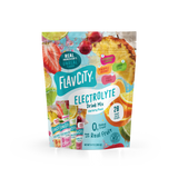 A stand-up pouch of Shop FlavCity Variety Pack Electrolyte Mix surrounded by fresh fruit, featuring 28 single-serve sticks in four flavors: strawberry limeade, pineapple coconut, lemon lime, and fruit punch.